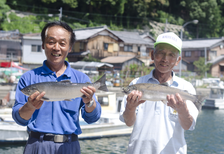 沖島漁港でビワマスを手にする森田さんと中島さん